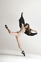 Image showing Young beautiful dancer in beige swimsuit dancing on gray background