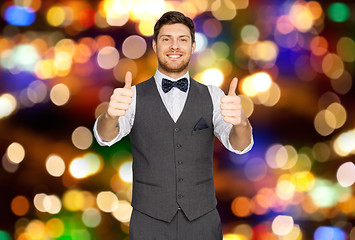 Image showing happy man in suit showing thumbs up over lights 