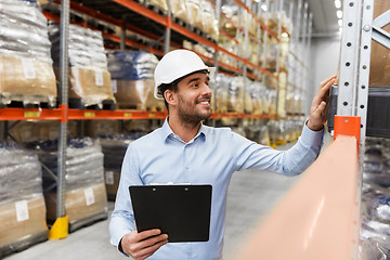 Image showing businessman in helmet with clipboard at warehouse