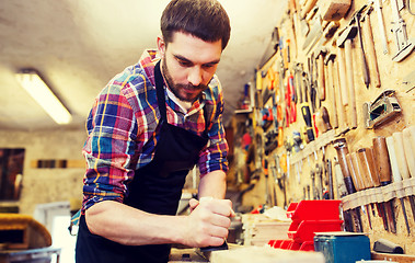 Image showing carpenter working with plane and wood at workshop