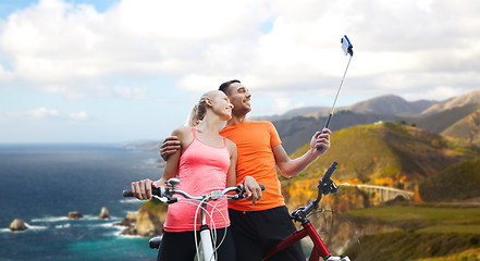 Image showing couple with bicycle and smartphone selfie stick