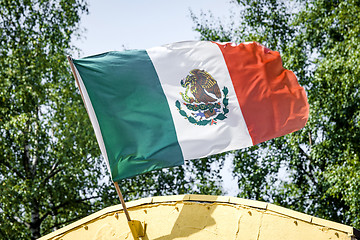 Image showing Mexican flag on a yellow building waving