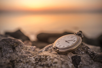 Image showing Antique watch on a rock in the sunrise