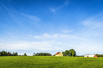 Image showing Yellow farmhouse on a rural green field