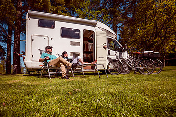 Image showing Woman with a man resting near motorhomes in nature. Family vacat