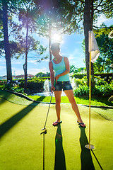 Image showing Mini Golf - Woman playing Golf on green grass at sunset