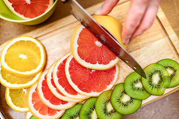 Image showing Women\'s hands Housewives cut with a knife fresh grapefruit on th