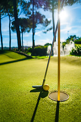 Image showing Mini Golf yellow ball with a bat near the hole at sunset