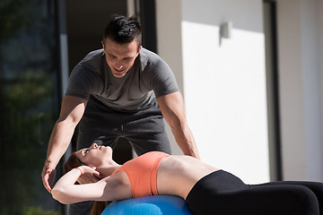 Image showing woman and personal trainer doing exercise with pilates ball