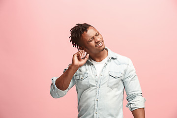 Image showing The Ear ache. The sad Faro-American man with headache or pain on a pink studio background.