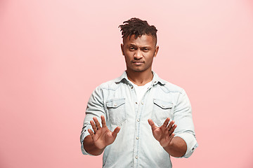 Image showing Young man with disgusted expression repulsing something, isolated on the pink