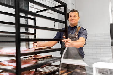 Image showing seller with smoking tray at fish shop