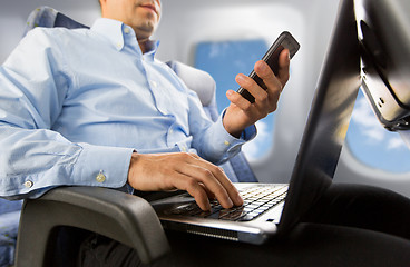 Image showing businessman with smartphone and laptop in plane