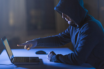 Image showing hacker pointing at laptop computer in dark room