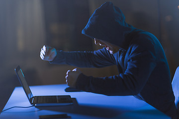 Image showing angry hacker with laptop shouting in dark room