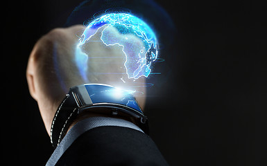 Image showing hand with smart watch and earth hologram