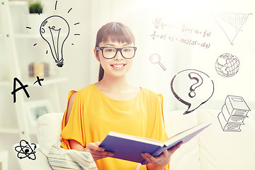 Image showing smiling young asian woman reading book at home