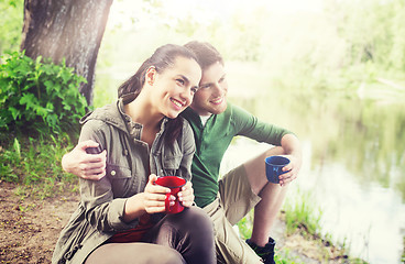 Image showing happy couple with cups drinking in nature