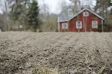 Image showing farmhouse in blur behind a plowed field