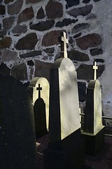 Image showing tombstones with crosses in the cemetery near the church wall