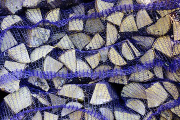 Image showing birch firewood in nets in the clay