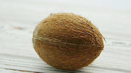 Image showing Unpeeled brown coconut on table