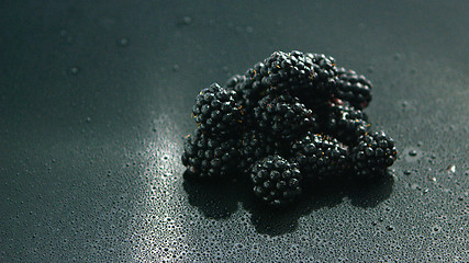 Image showing Pile of shiny blackberries on wet surface