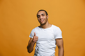 Image showing The happy businessman standing and smiling against orange background.