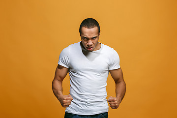 Image showing The young emotional angry man screaming on orange studio background