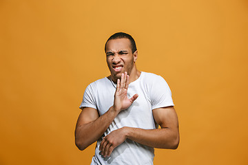 Image showing The young man whispering a secret behind her hand over orange background