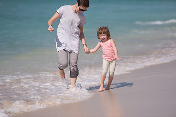 Image showing mother and daughter running on the beach