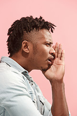 Image showing The young Afro-American man whispering a secret behind her hand over pink background