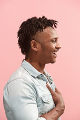 Image showing The happy business Afro-American man standing and smiling against pink background. Profile view.