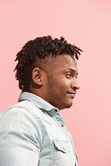 Image showing The happy business Afro-American man standing and smiling against pink background. Profile view.