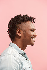 Image showing The happy business Afro-American man standing and smiling against pink background. Profile view.