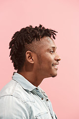 Image showing The happy business Afro-American man standing and smiling against pink background. Profile view.