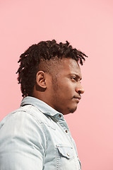 Image showing The suspicious business Afro-American man standing and suspiciously looking against pink background. Profile view.