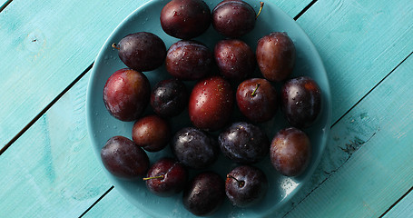 Image showing Wet plums on blue plate on table