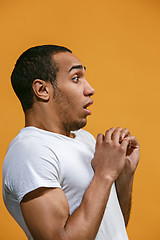 Image showing Doubtful Afro-American man is looking frightenedly against orange background