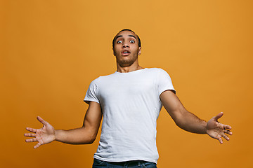 Image showing The young attractive man looking suprised isolated on orange