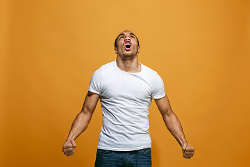 Image showing The young emotional angry man screaming on orange studio background