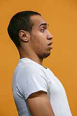 Image showing Doubtful Afro-American man is looking frightenedly against orange background