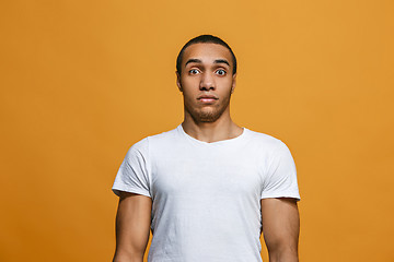 Image showing The young attractive man looking suprised isolated on orange