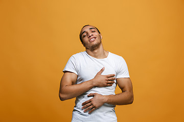 Image showing The happy businessman standing and smiling against orange background.