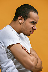 Image showing Angry Afro-American man is looking serious against orange background