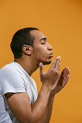 Image showing Lovely Afro-American man is making air kiss against orange background