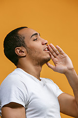 Image showing Happy Afro-American man is shouting against orange background