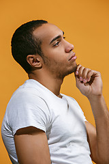 Image showing Thoughtful Afro-American man is looking thoughtfully against orange background