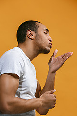 Image showing Lovely Afro-American man is making air kiss against orange background