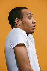 Image showing Frustrated Afro-American man is looking frightenedly against orange background